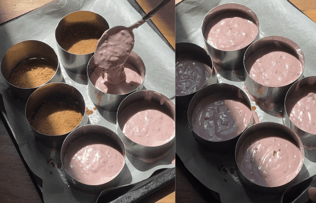 Gluten-free raspberry cheesecake batter being spooned into individual round molds lined with parchment paper, with prepared crusts visible.