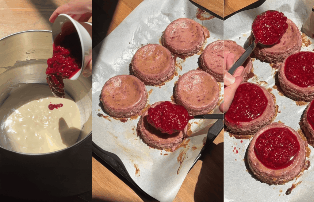 Raspberry compote being spooned onto baked gluten-free mini cheesecakes arranged on a lined baking tray.
