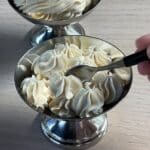 Spoon scooping soft Italian meringue buttercream from a piped dessert dish.