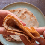 Close-up of a cooked almond flour tortilla showing golden brown spots and soft interior.