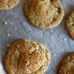 Freshly baked almond flour cookies cooling on parchment paper with cracked tops.