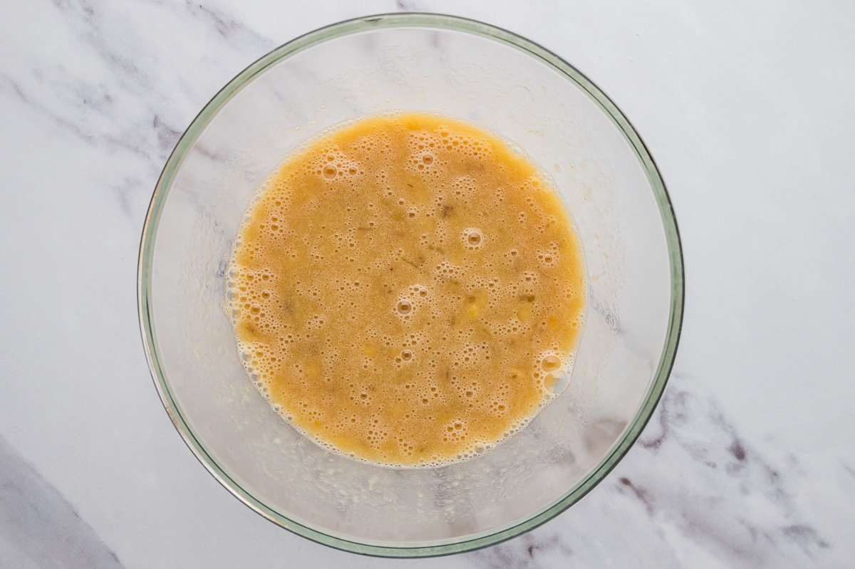 Mashed bananas and wet ingredients in a large mixing bowl for almond flour banana bread.