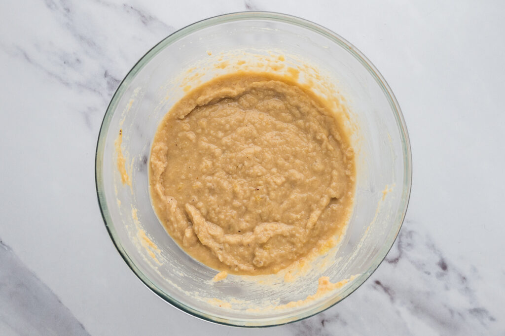 Banana bread batter being mixed in a bowl with almond flour and dry ingredients added.