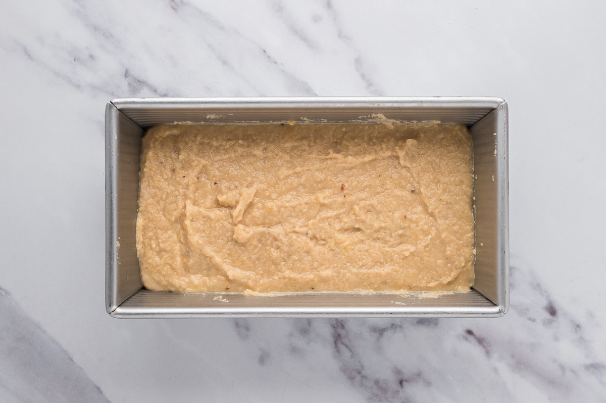 Almond flour banana bread batter poured into a parchment-lined loaf pan ready for baking.
