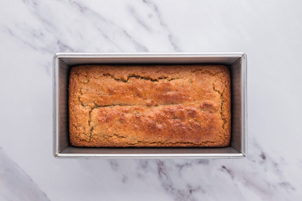 Golden brown almond flour banana bread baked in a loaf pan fresh from the oven.
