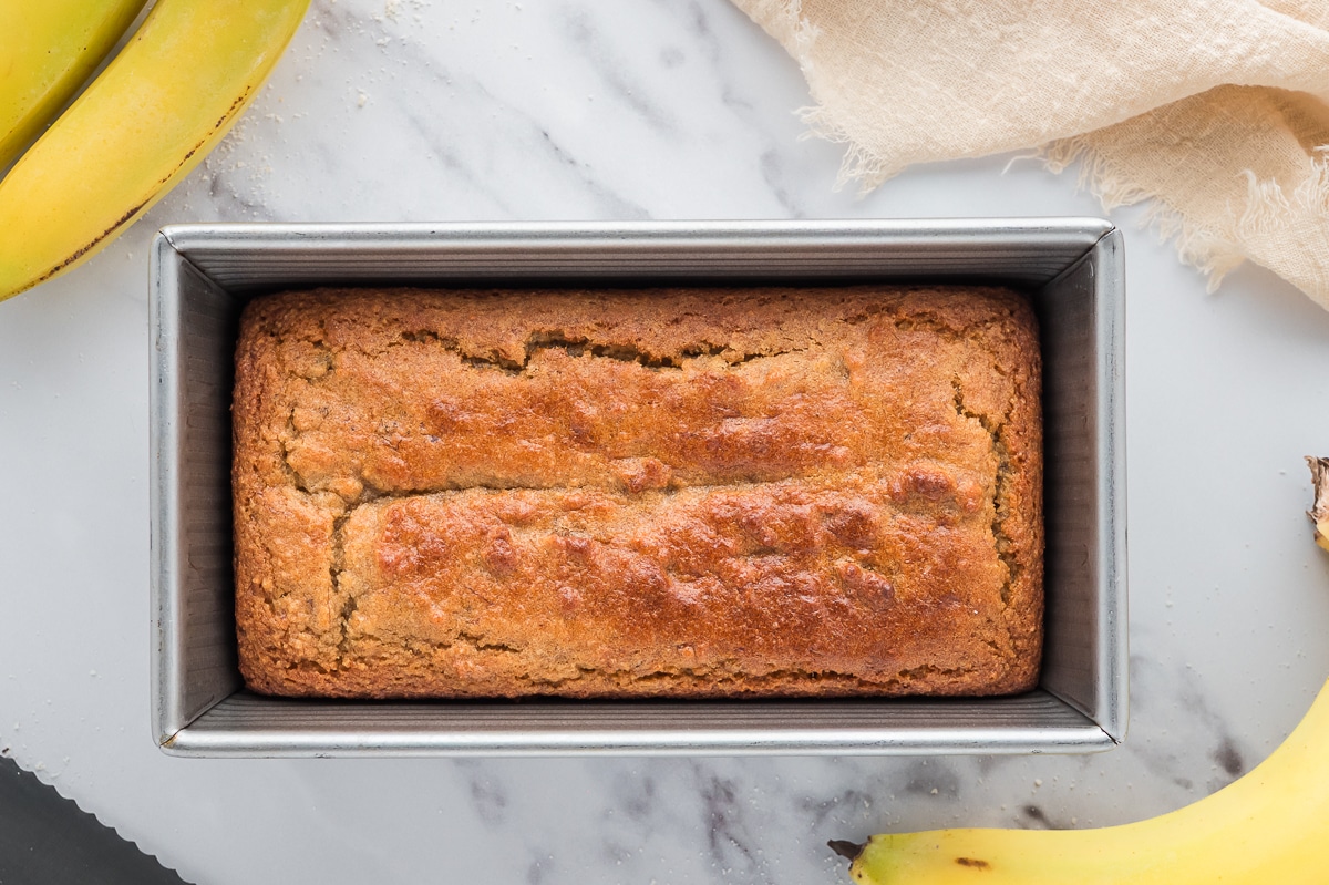 Full loaf of almond flour banana bread in a silver baking tray viewed from above.