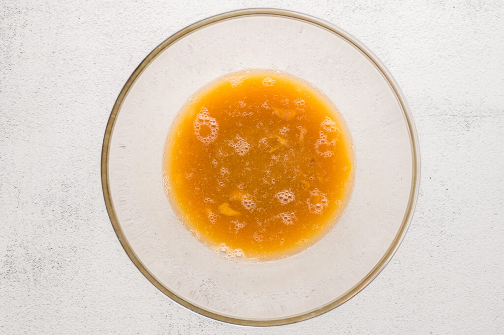 Whisking eggs, oil, and maple syrup together in a large mixing bowl for almond flour muffins