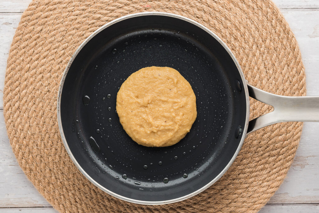 Almond flour pancake cooking in a non-stick skillet with golden edges forming