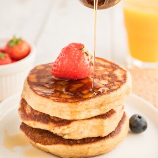 Almond flour pancakes with syrup pouring over stack