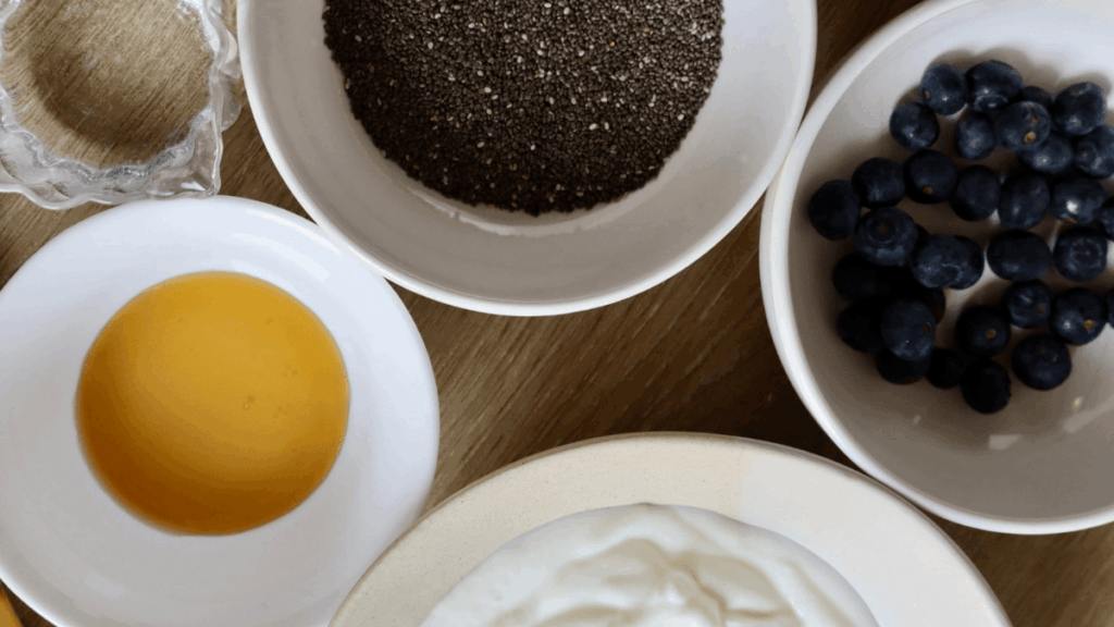 Blueberry chia jam ingredients laid out on a counter including blueberries, chia seeds, honey, and yogurt