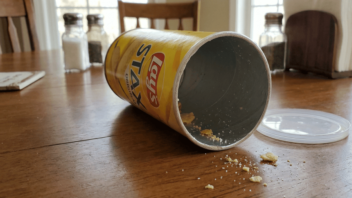 A cannister of Lay's Stax laying open on the dining room table.